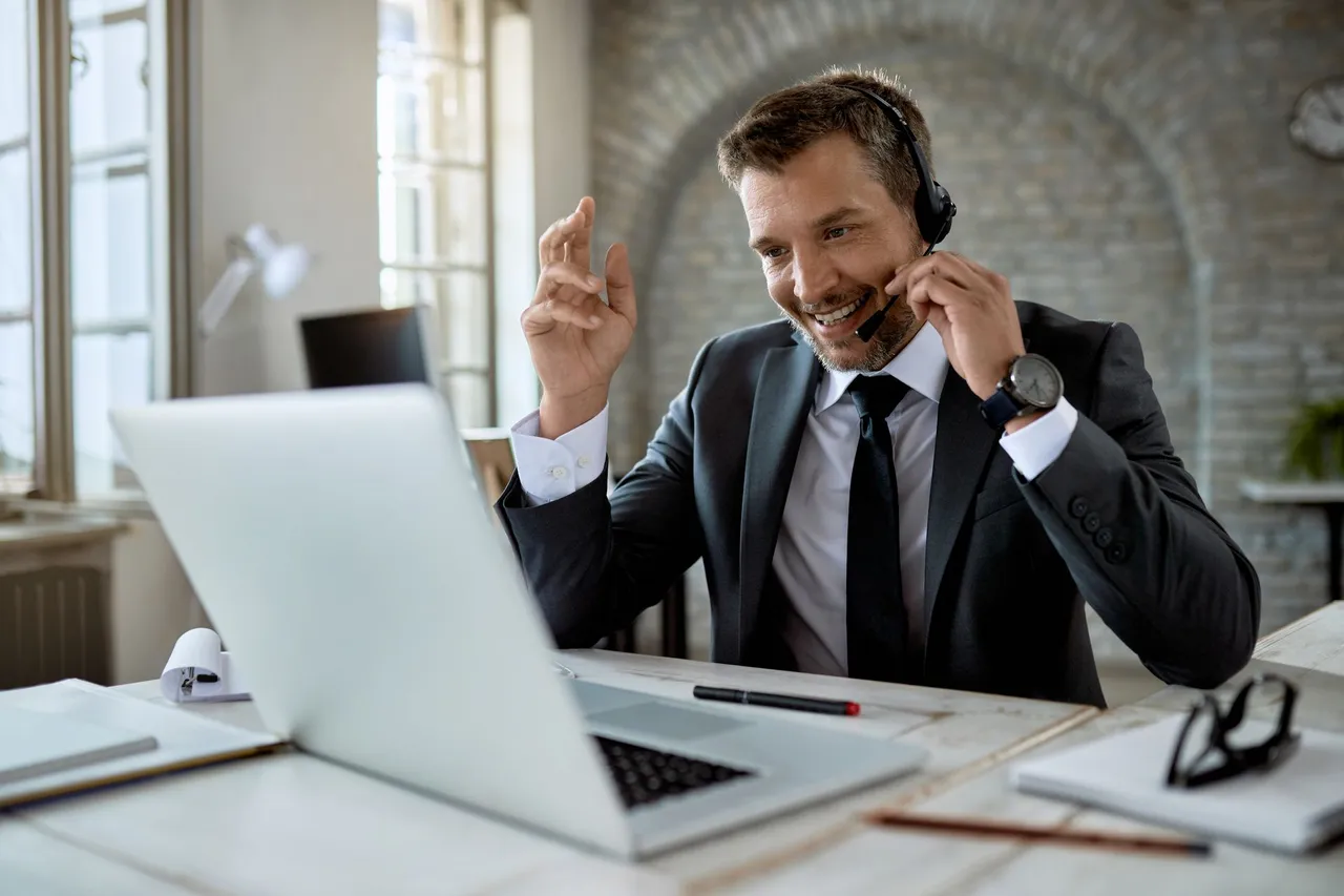 Businessman wearing a headset on a VoIP call at his laptop
