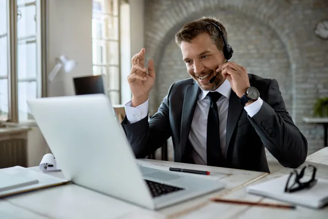 Businessman wearing a headset on a VoIP call at his laptop